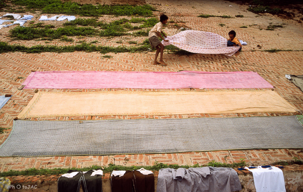 Varanasi o Benarés (estado de Uttar Pradesh). Dos niños extienden saris y otras prendas para su secado.