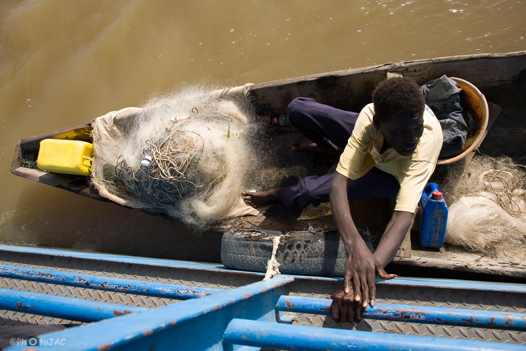 Segou (Mali). Embarcación típica, conocida con el nombre de pinaza. Hombre de etnia bozo (pescadores) con las redes preparándose para salir a pescar.