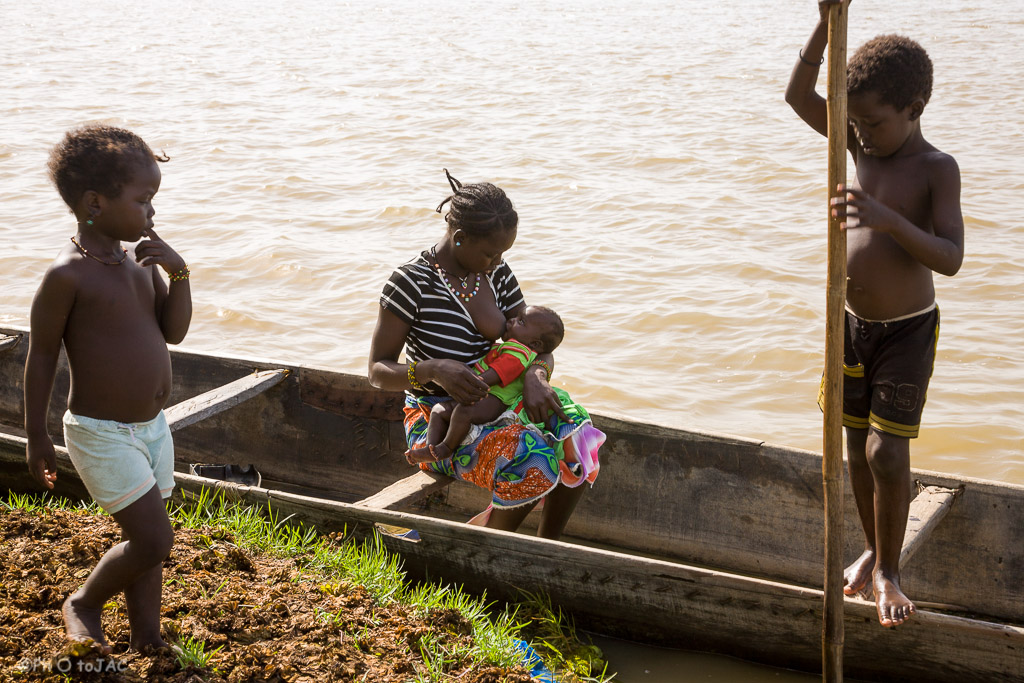 Una madre amamanta a su hijo sobre una pinaza (embarcación típica de madera) en la aldea de etnia bozo que hay frente a Segou, al otro lado del Niger. Mali.