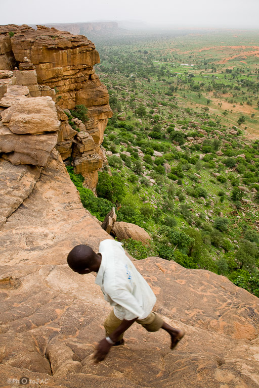 País Dogón. Mali. Falla de Bandiagará: Falla geológica de 150 kilómetros de longitud cuyo desnivel alcanza los 300 metros. Un hombre se desplaza por las rocas al borde del acantilado.