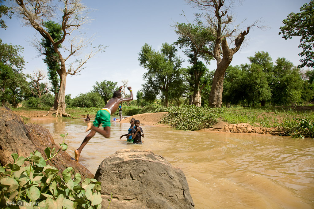 País Dogón. Mali. Aldea de Tireli. Niños se divierten saltando al cauce de un pequeño río desde las rocas de la orilla.