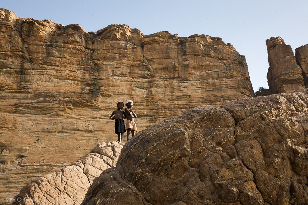 País Dogón. Mali. Aldea de Nombori. Niños jugando sobre las rocas. Al fondo las paredes de la falla de Bandiagara.