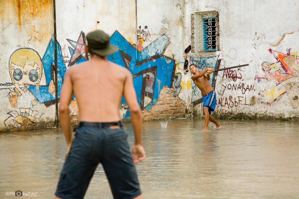 La Habana. Dos jóvenes jugando al beisbol tras un chaparrón.