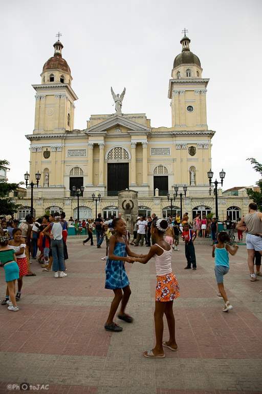 Santiago de Cuba. Niños bailando al atardecer en el Parque Céspedes, con la Catedral de Nuestra Señora de la Asunción al fondo.