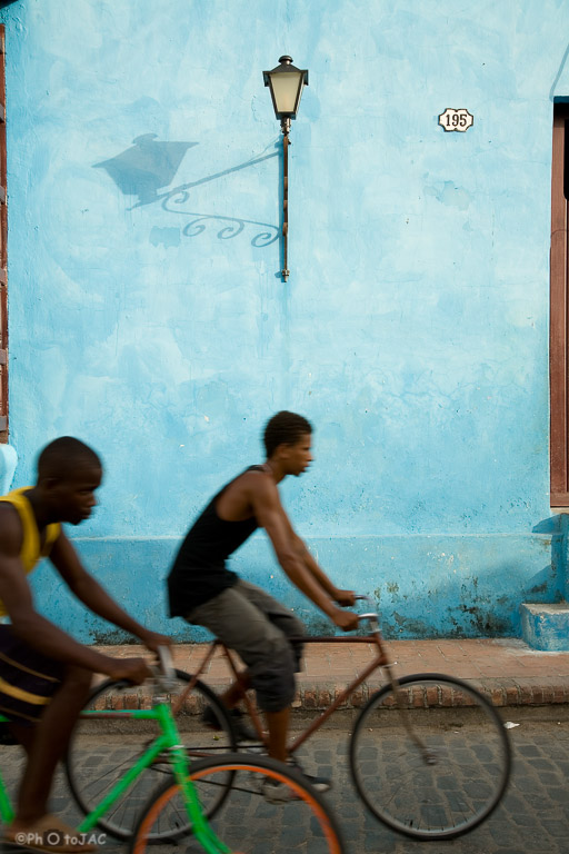 Camagüey. Fachada en la Plaza de San Juan de Dios. Jóvenes en bicicleta.