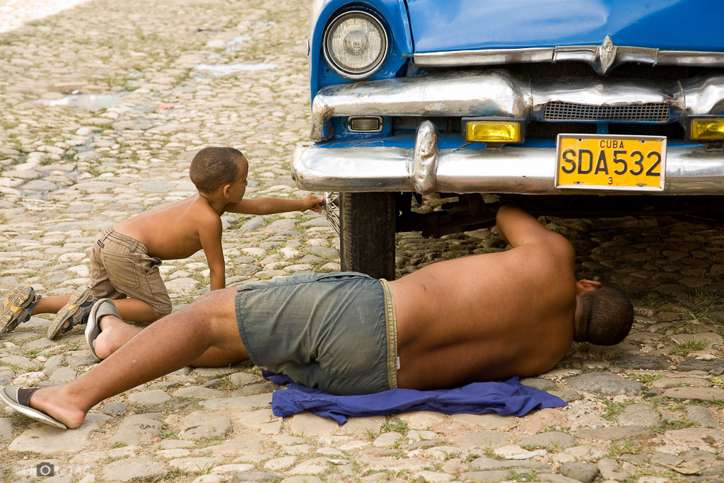 Trinidad ( provincia de Sancti Spíritus). Reparando un vehículo antiguo en las calles empedradas del casco antiguo.
