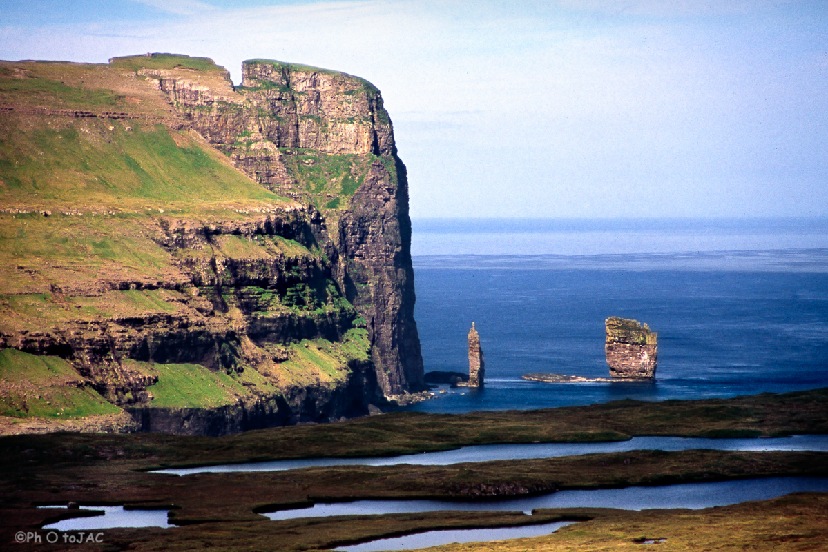 Isla de Eysturoy. Acantilados cercanos a Eidi. Los dos bloques que aparecen en la imagen son conocidos como "Risin" (71m, dcha.) y "Kellingin" (68m, izqda.), que traducido es "el gigante y la bruja". Hay una antigua leyenda sobre su origen.