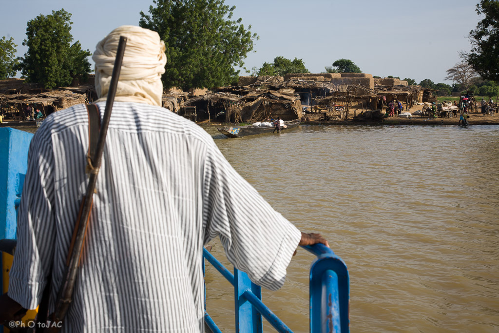 Segou (Mali). Embarcación cruzando el río Niger, transportando pasajeros desde Segou a una aldea de etnia bozo en la orilla opuesta. Detalle de un pasajero con un arma de fuego.