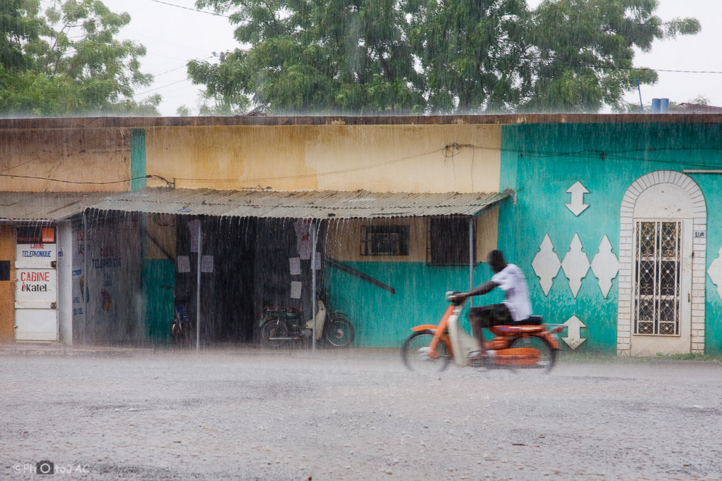 Un hombre en moto circula bajo una intensa lluvia, por las calles de la ciudad de Segou. Mali.