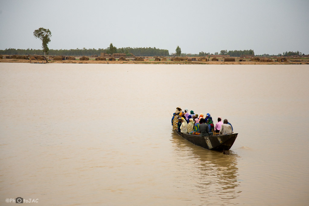 Mali: Puerto de Mopti. Embarcación local hecha de madera, llamada "pinaza", cruza el río Niger cargada de pasajeros. Al fondo un poblado de etnia bozo (pescadores).