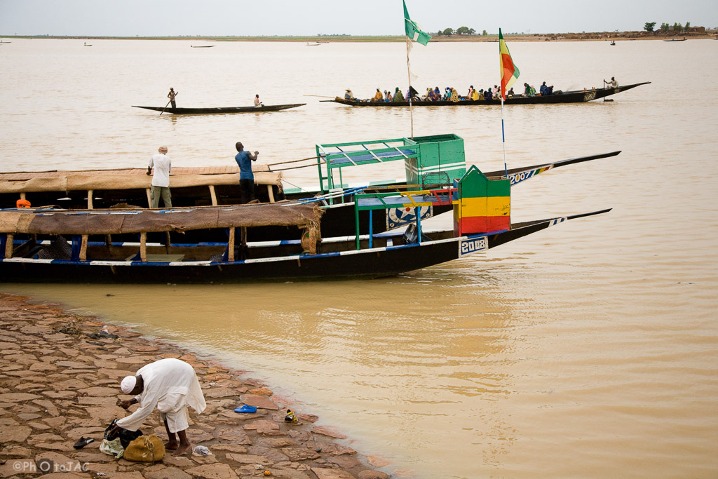 Mali: Puerto de Mopti. Embarcaciones locales hechas de madera llamadas "pinazas". Una de ellas cruza el río Niger cargada de pasajeros.