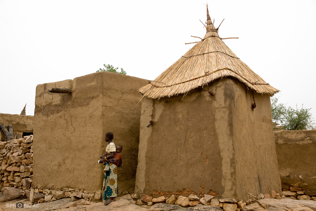 País Dogón. Mali. Una madre transporta a su hijo. Graneros erigidos con adobe en la aldea de Daga.