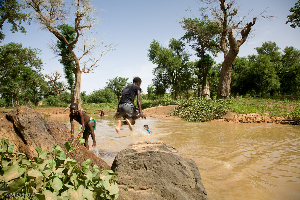 País Dogón. Mali. Aldea de Tireli. Niños se divierten saltando al cauce de un pequeño río desde las rocas de la orilla.