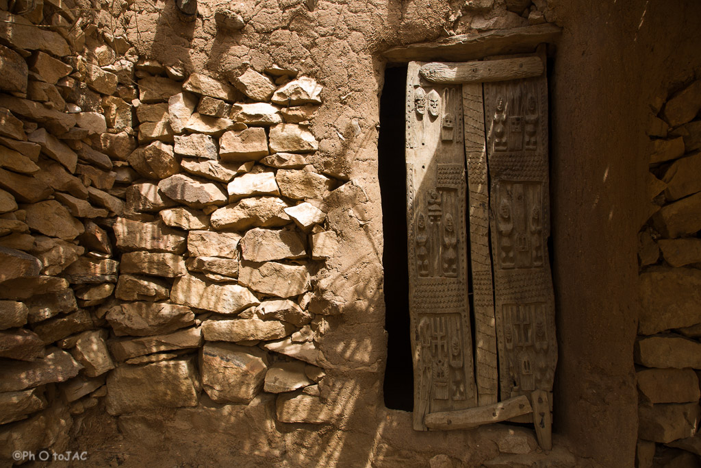 País Dogón. Mali. Aldea de Begnimato. Fachada de una vivienda erigida con madera, adobe y piedra. Detalle de la puerta de madera bellamente tallada.